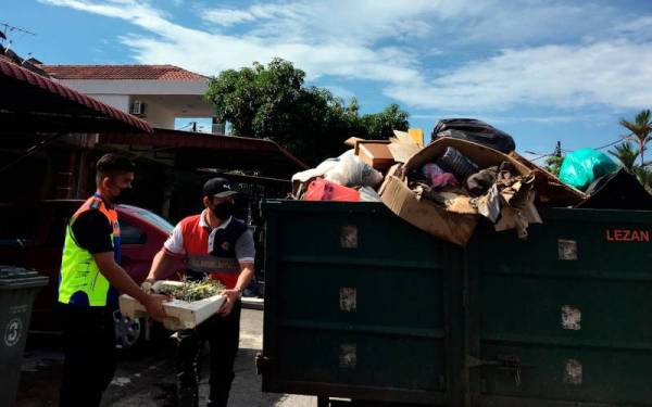 Khairuladha (kanan) bersama petugas mengutip sisa pepejal pada operasi pembersihan pasca banjir di Taman Merdeka Jaya Batu Berendam, pada Rabu. - Foto Bernama 