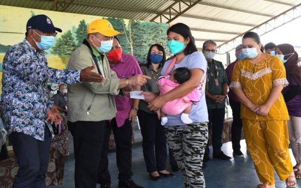 Hajiji (dua, kiri) menyampaikan sumbangan kepada mangsa-mangsa banjir di daerah Kota Marudu ketika melakukan lawatan di daerah itu pada Rabu. - Foto Bernama 