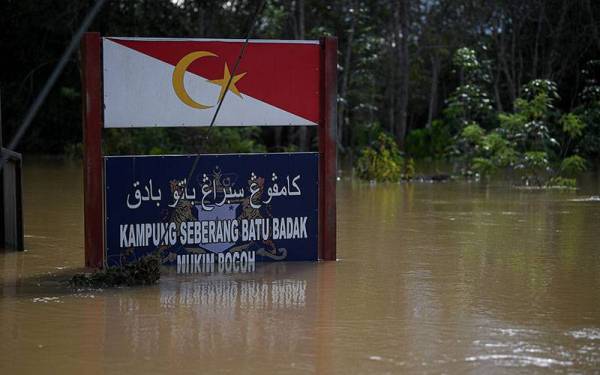 Papan tanda Kampung Seberang Batu Badak yang hampir ditenggelami air setinggi 14 kaki akibat banjir di Kampung Seberang Batu Badak, hari ini.