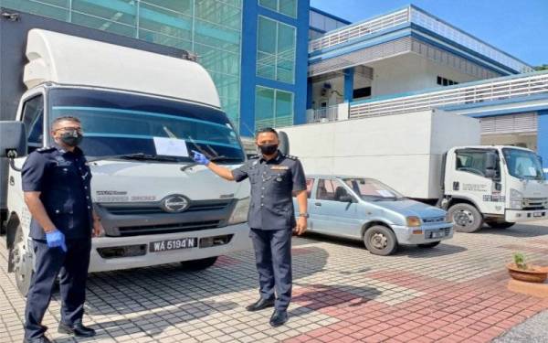 Nor Omar (kanan) menunjukkan dua lori dan sebuah kereta yang turut disita hasil pemeriksaan di tepi jalan kawasan Kampung Bharu, Seri Manjung, pada Rabu.