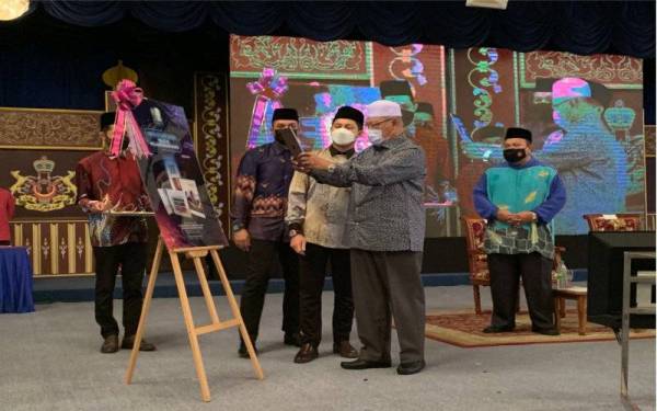 Ahmad (tengah) melakukan imbasan kod sebagai gimik perasmian sebuah buku di Majlis Amanat Tahun Baharu 2022 di Dewan Jamuan Utama, Kompleks Kota Darul Naim, Kota Bharu pada Khamis.