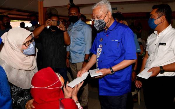 Ismail Sabri (dua dari kanan) beramah mesra bersama mangsa banjir ketika menyampaikan sumbangan berjumlah RM1,000 semasa melawat PPS di Sekolah Kebangsaan Gangsa, Alor Gajah pada Selasa. - Foto Bernama