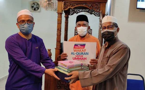 Ibrahim (kanan) ketika menerima sumbangan set naskah al-Quran pada Khamis di Surau Hamideen sambil disaksikan oleh Hashim (tengah).