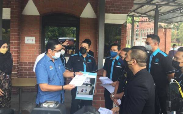 Hariss (kiri) menerima memorandum yang diserahkan Hishamuddin dan Mohd Yusuf di pintu masuk Kementerian Sumber Manusia di Putrajaya pada Jumaat.