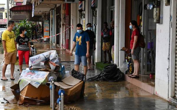 Kelihatan para peniaga mengeluarkan barangan mereka dari kedai untuk dibersihkan dan ada yang terpaksa dibuang selepas rosak akibat banjir pada 20 Disember lalu. - Foto Bernama
