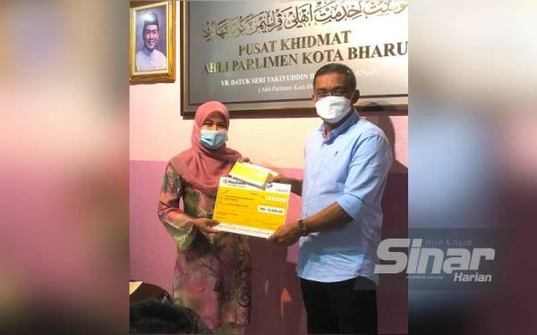 Takiyuddin (kanan) menyerahkan cek sumbangan kepada tujuh persatuan, NGO dan kelab di Pusat Khidmat Ahli Parlimen Kota Bharu pada Ahad.