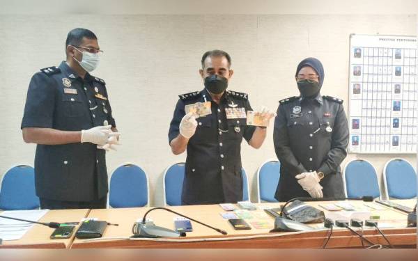 Abdul Majid (tengah) menunjukkan dolar yang berjaya dirampas ketika sidang akhbar di IPK Melaka di Bukit Beruang, pada Selasa.