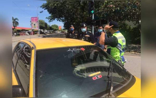 Mohd Zaidi (dua dari kiri) membuat pemeriksaan Proton Wira yang ditinggalkan suspek dalam kejadian di Jalan Tun Fuad, Kota Kinabalu pada Selasa.
