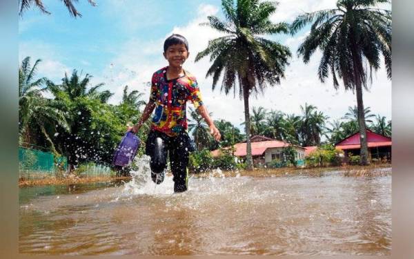 Kanak-kanak, Muhammad Amsyar Amran, 10, bermain air banjir di kawasan rumahnya ketika tinjauan di Kampung Lanchang pada Selasa. - Foto Bernama