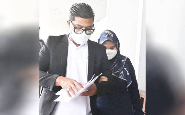 Fatimah (kanan) ditemani suaminya ketika keluar dari Mahkamah Sesyen di Melaka pada Rabu atas dua pertuduhan menerima suapan.