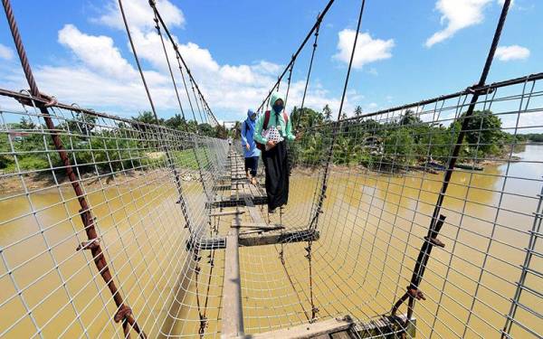 Beberapa pelajar Sekolah Kebangsaan Sibuga Besar terpaksa menggunakan jambatan gantung yang sudah usang dan tidak dibaiki pada hari pertama sesi persekolahan ketika tinjauan di Kampung Nelayan Tengah. - Foto Bernama