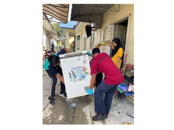 Sukarelawan sedang fokus membaikpulih penghawa dingin yang rosak akibat banjir.