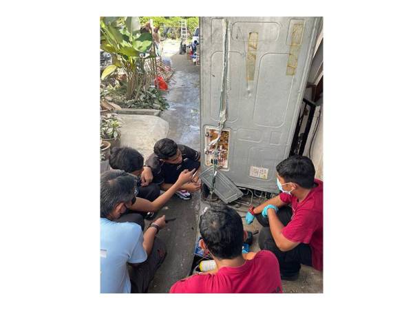 Tenaga Pengajar Kolej KEDA, Abd Halim Mehat (tengah) memberi tunjuk ajar kepada sukarelawan yang merupakan pelajar teknologi elektrik.