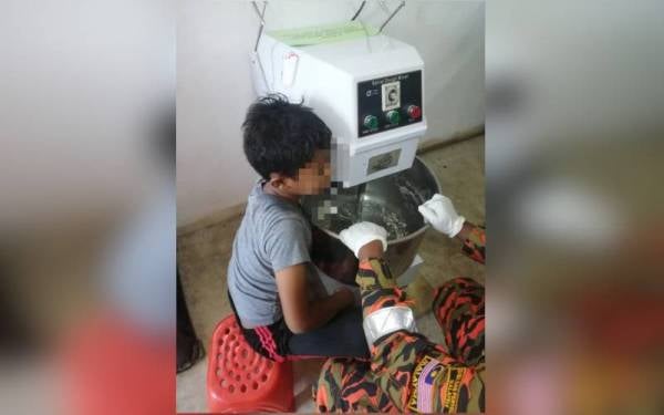 Kanak-kanak lelaki itu berjaya diselamatkan bomba selepas tangan kirinya tersepit pada mesin penguli tepung. - Foto ihsan bomba