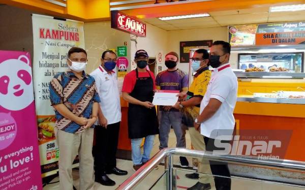 Zainol Fadzi (dua dari kanan) menyerahkan dokumen pinjaman yang diluluskan kepada Mohammed Shofni Khoiri ketika Program Walkabout Usahawan Tekun di Angsana Mall Ipoh pada Khamis.