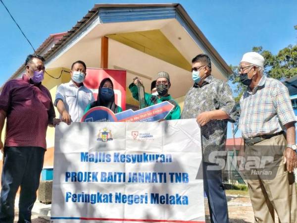 Ab Rauf (dua,kanan) bersama Abu Shah (tiga,kanan) dan isterinya bergambar di depan rumah baharu du Kampung Pulau, di sini, pada Jumaat.