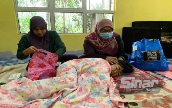 Tuan Zaimah (kanan) mengusap muka Putri Noor Zafrina yang sedang menahan sakit gigi di rumahnya di Tasek Bakong, Rantau Panjang pada Jumaat.