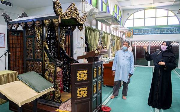 Dr Harleny (kanan) bersama Imam Muda Masjid Ar Rahman Kampung Surau Pasir Pekan, Wan Mohamad Wan Mohamed Nor menunjukkan kehalusan ukiran bermotifkan Bunga Ketumbit dan Daun Kerak Nasi yang diperbuat daripada tangan pada mimbar yang berusia 400 tahun di Masjid Ar Rahman Kampung Surau Pasir Pekan, Wakaf Bharu di sini. - Foto Bernama