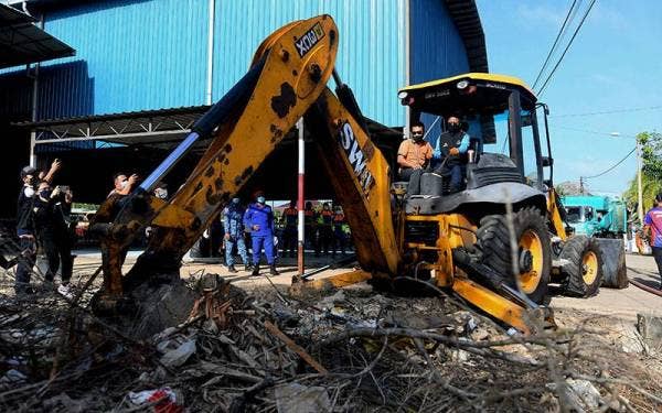 Ismail (kanan) mengendalikan jengkaut ketika membantu kerja-kerja pembersihan pasca banjir di Kampung Baru Lenga pada Ahad. -Foto Bernama
