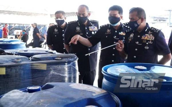 Ayob Khan (kanan) menunjukkan tong-tong bahan kimia di kilang yang dijadikan sebagai makmal memproses ketamin di Kawasan Perindustrian Pusing, Batu Gajah.