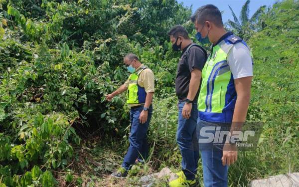 Ramli (kiri) menunjukkan lokasi persembunyian suspek iaitu kira-kira 50 meter dari belakang rumahnya sebelum diberkas polis pada Sabtu.