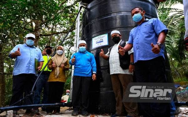 Tuan Ibrahim (tiga dari kanan) bersama Mohd Zakhwan (dua dari kanan), Mohd Rodzwan (kiri) dan Khairun Nissa (empat dari kanan) di tapak projek Wakaf Air di Jalan Temalian, Felda Sungai Retang pada Ahad.