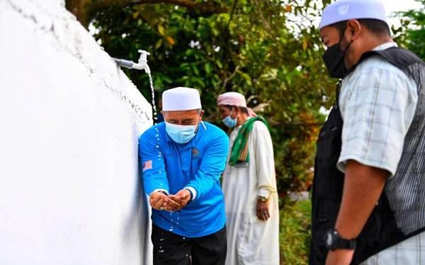 Tuan Ibrahim mencuba air menerusi projek Wakaf Air di Jalan Jengkuar di Felda Sungai Retang pada Ahad.