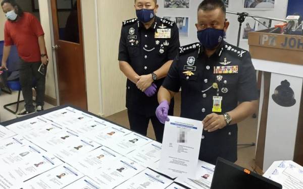 Kamarul Zaman menunjukkan gambar suspek yang terlibat dengan sindiket pemalsuan sijil vaksin.