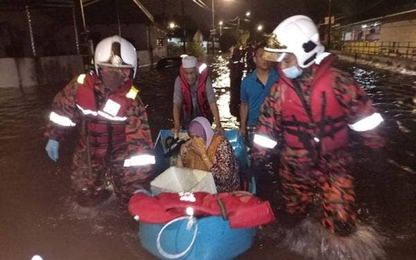 Anggota bomba membantu memindahkan seorang warga emas ke lokasi lebih selamat susulan kejadian banjir kilat di beberapa kawasan perumahan di Ipoh pada Rabu. - Foto: Bomba Perak