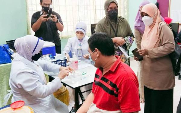 Dr Nor Azimi (belakang, dua kanan) meninjau program outreach pemberian vaksin dos penggalak kepada kumpulan OKU di PDK Kompleks Penyayang JKM Pahang di sini pada Khamis.