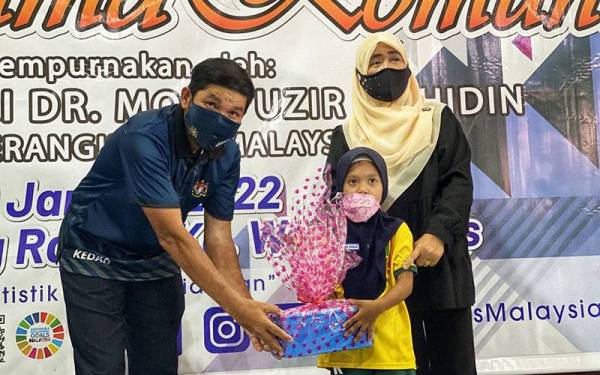 Mohd Uzir (kiri) menyampaikan hadiah kepada pemenang pertandingan mewarna di Program Sesi Bersama Komuniti di Kampung Wang Tepus, Jitra di sini pada Khamis.