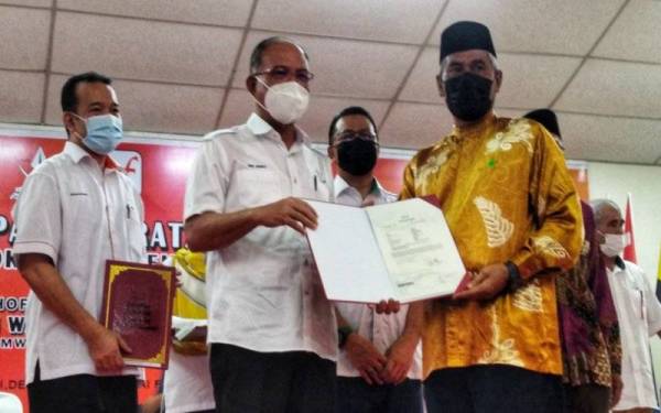 Wan Rosdy (dua, kanan) menyerahkan suratan hak milik peneroka Felda Kemasul di Bentong pada Sabtu. 