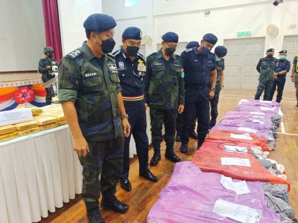 Hazani (kiri) menunjukkan 17 bungkusan plastik berwarna ungu dan merah mengandungi dadah yang ditemui di dalam Toyota Hilux.