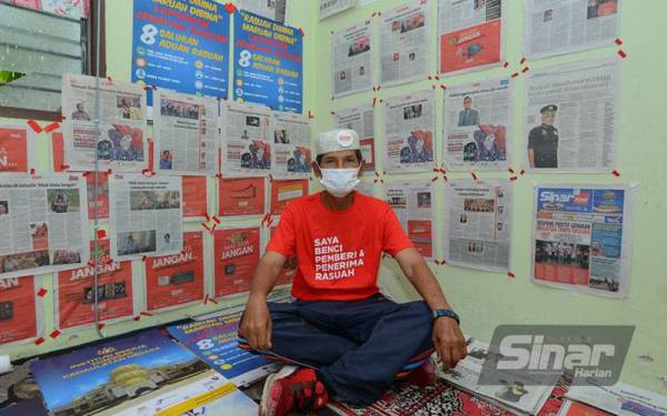 Mohd Haris Samsudin bersama sebahagian koleksi keratan artikel Rasuah Busters yang ditampal di kediaman sementaranya di Kuala Pilah, Negeri Sembilan.