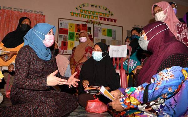 Rina meluangkan masa beramah mesra bersama penduduk kampung yang merupakan mangsa banjir pada Program Penyampaian Kotak Makanan Yayasan Kebajikan Negara dan Kit Dana Kasih Lembaga Penduduk dan Pembangunan Keluarga Negara di Balai Raya Kampung Spang Loi dekat Batu Anam, pada Ahad. - Foto Bernama
