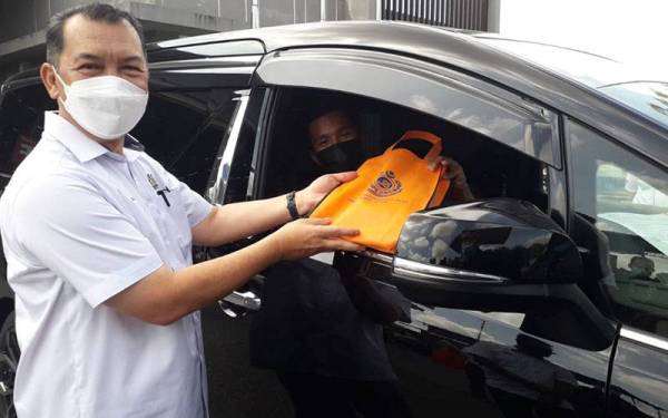 Mohd Solihan menyerahkan risalah kepada penerima selepas Majlis Pelancaran Kempen Keselamatan Jalan Raya Musim Perayaan Tahun Baru Cina di Puspakom Senai, Kulai pada Ahad.