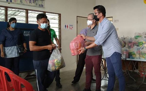 Kar Hing (kanan) menyampaikan sumbangan kepada mangsa banjir pada Majlis Sumbangan Pasca Banjir Kampung Baru Ampang di Pertubuhan Faedah Bersama Ampang Baharu, Kampung Ampang Baru, Ipoh pada Selasa.