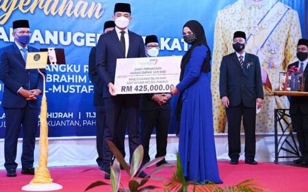 Nur Saidatul Akma menyerahkan replika pembayaran zakat RM425,000 kepada Tengku Hassanal pada majlis penyerahan zakat perniagaan dan anugerah zakat di Hotel Grand DarulMakmur di sini pada Selasa.