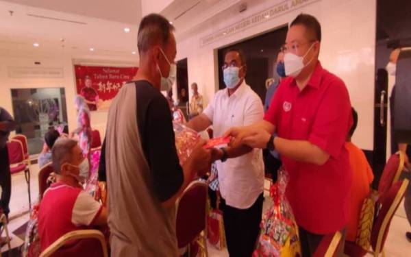 Muhammad Sanusi (tengah) menyampaikan hamper kepada seorang penduduk dengan ditemani Exco Perumahan, Alam Sekitar, Perpaduan dan Hal Ehwal Masyarakat Cina dan Siam Kedah, Dr Robert Ling Kui Ei (kanan) dalam Program Penyampaian Hamper sempena Tahun Baharu Cina di Wisma Darul Aman, pada Selasa.