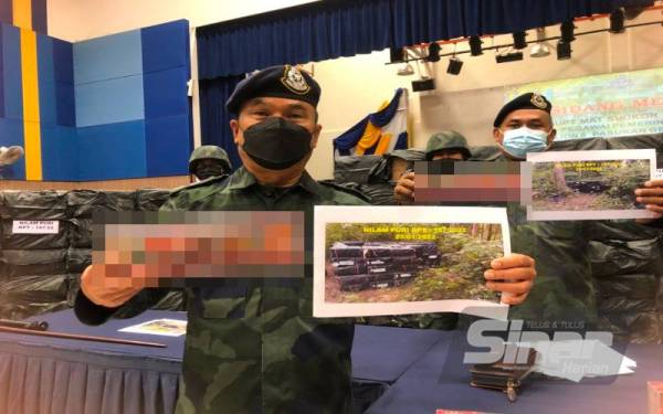 Mat Shukor (kiri) menunjukkan gambar lokasi semak yang menjadi tempat penyeludup menyembunyikan rokok bernilai RM1.6 juta.