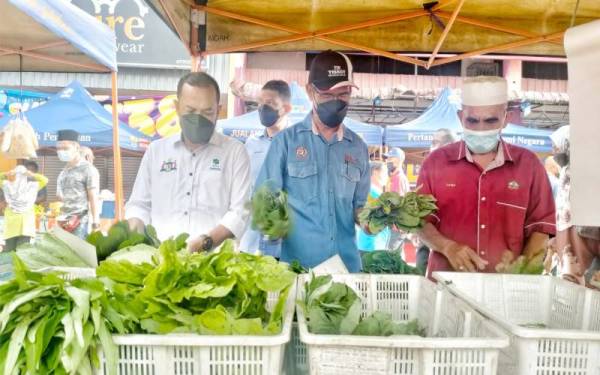 Ghazale (tengah) dan Hairudin (kiri) melihat sayur-sayuran ketika program Jualan Pasar Tani Khas sempena Tahun Baharu Cina 2022 di Pasar Tani Rim Jasin di sini, pada Rabu.