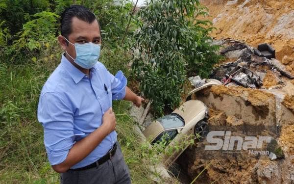 Mohd Nazir menunjukkan kereta miliknya yang terjatuh ke dalam longkang akibat mendapan tanah di Jalan LP 1A/2 Lestari Perdana, Bandar Putra Permai di sini pada Rabu.
