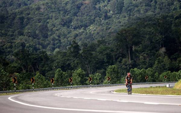 Seorang penunggang basikal melalui Lebuhraya Temiang-Pantai yang menjadi lokasi dan tumpuan orang ramai berhenti untuk mengambil gambar kerana keindahan panoramanya ketika tinjauan hari ini.