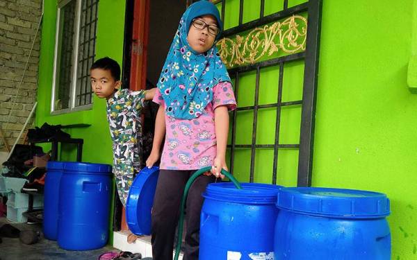 Nurin Zahirah 9, membantu ibunya, Nurhidayah mengisi air dalam tong di Taman Seri Bayu Sungai Lalang pada Rabu.