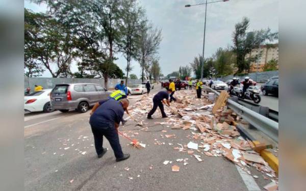 Pekerja pembersihan MBPP sedang membersihkan mozek yang bertaburan di lebuh raya selepas kemalangan.