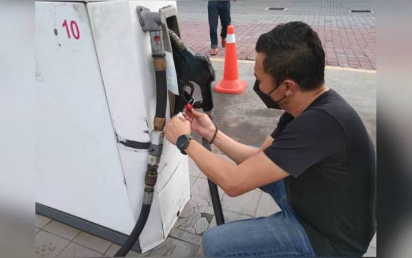 Salah seorang pegawai KPDNHEP Pulau Pinang sedang memeriksa pam minyak di stesen minyak berkenaan.