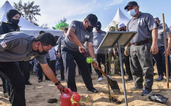 Tengku Farouk Husin (tengah) diiringi Roslan (kanan) melakukan gimik menanam anak pokok pada majlis gotong-royong sempena Kempen Penanaman 100 Juta Pokok di bawah Program Penghijauan Malaysia peringkat negeri Terengganu di Pantai Teluk Bidara pada Khamis. - Foto Bernama
