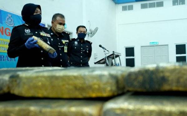 Surina (kiri) menunjukkan sebahagian dadah jenis ganja yang dirampas ketika sidang akhbar di Ibu Pejabat Polis Kontinjen Perlis pada Khamis.