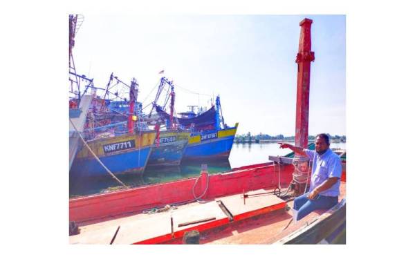 Azani menunjukkan sebahagian daripada bot-bot laut dalam yang tersadai di jeti Tok Bali, Pasir Puteh pada Khamis.