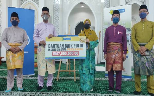 Saipolyazan (dua dari kiri) dan Salwana (tengah) memegang replika cek bantuan pasca banjir untuk institusi agama di Masjid Ar Rahmah, RTB Bukit Changgang, Kuala Langat pada Jumaat.